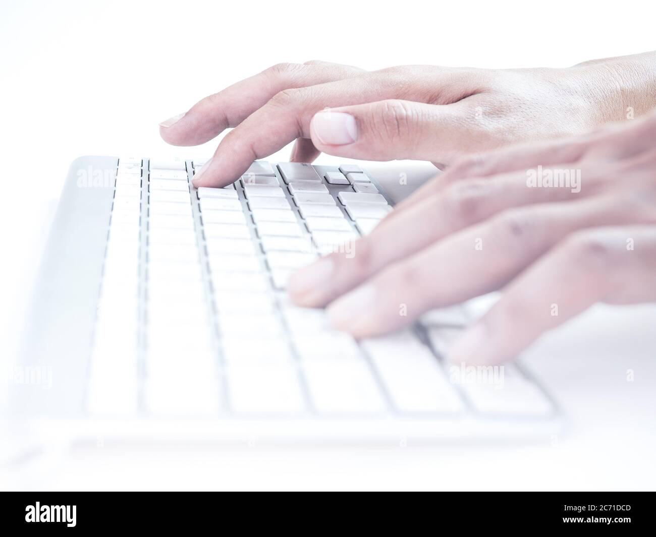 Close-up hands typing on remote control wireless computer keyboard on a white background. Stock Photo
