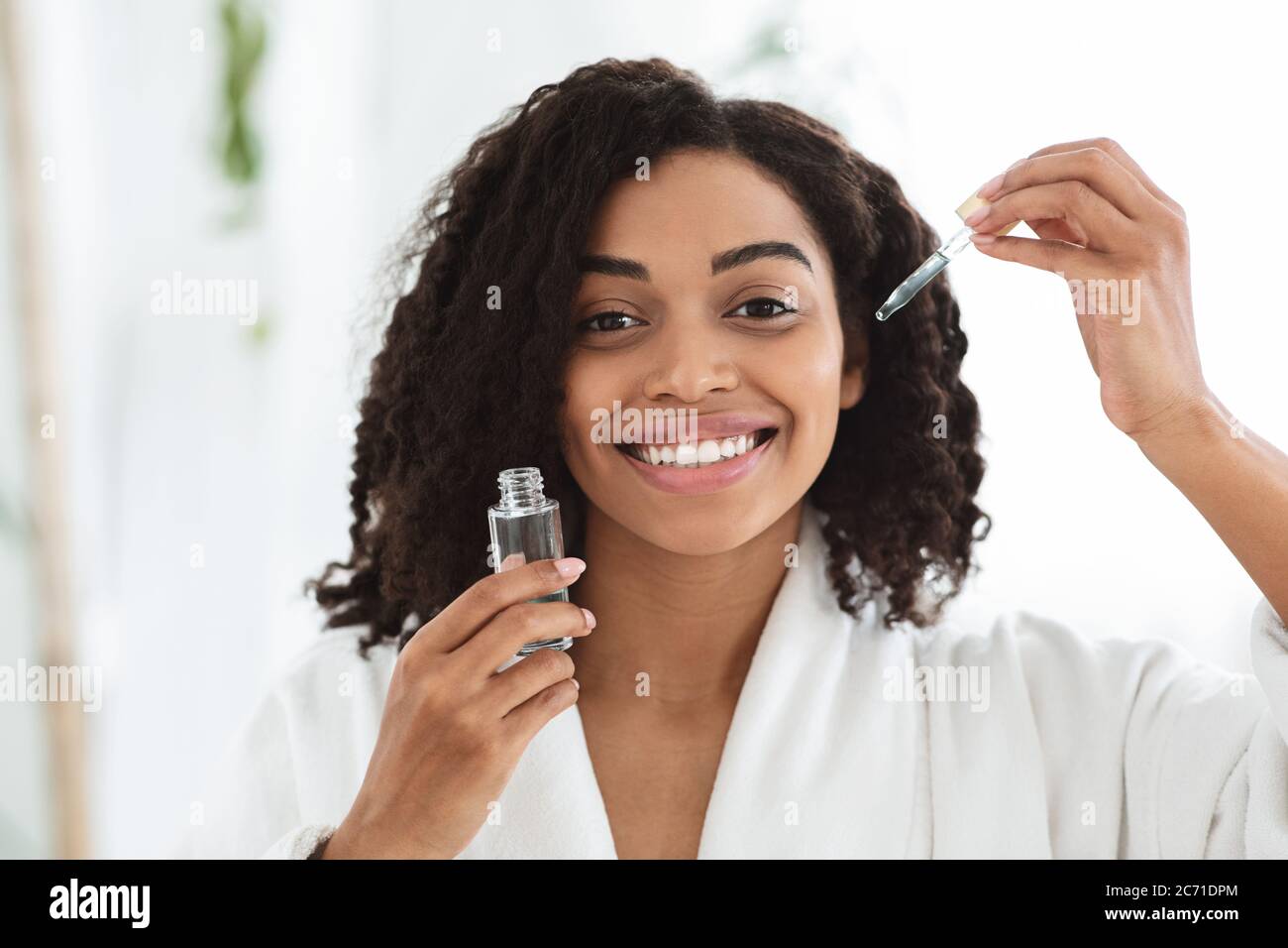 Skin Care Products. Smiling African Woman Holding Bottle With