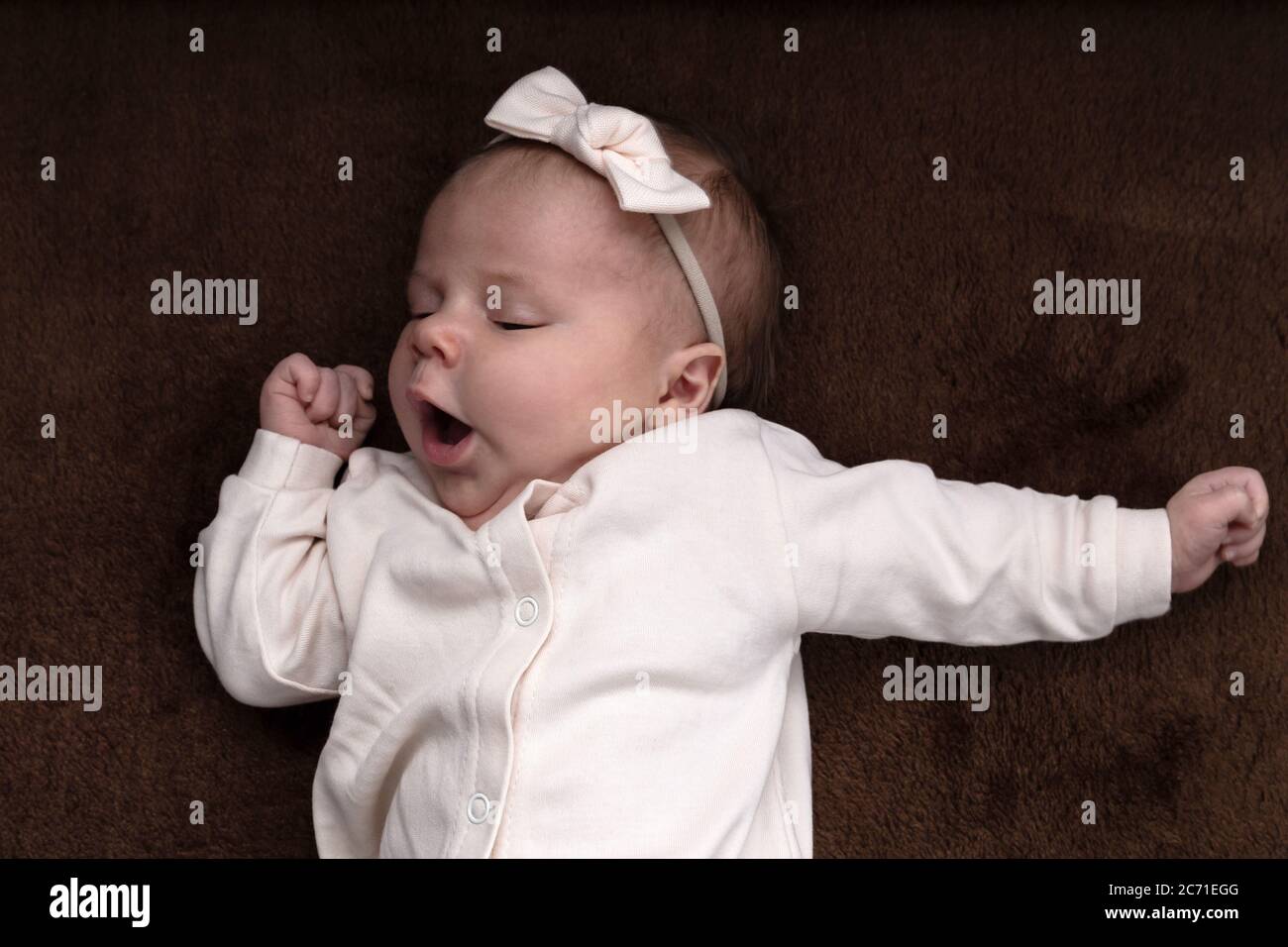 Newborn baby girl boy wants to sleep, rubs his eyes with his hand and