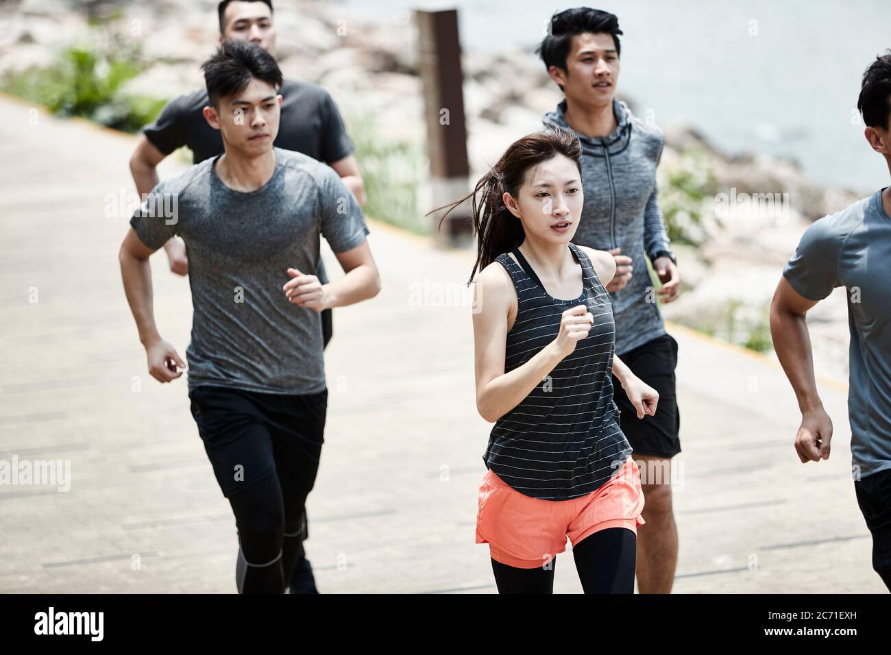 group of five young asian adult men and woman running training outdoors Stock Photo