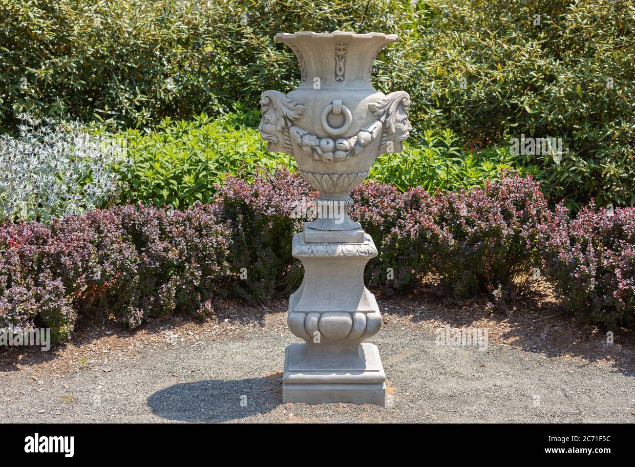 Landscape with formal garden with colorful shrubs and flowering plants with urn on bright sunny day Stock Photo