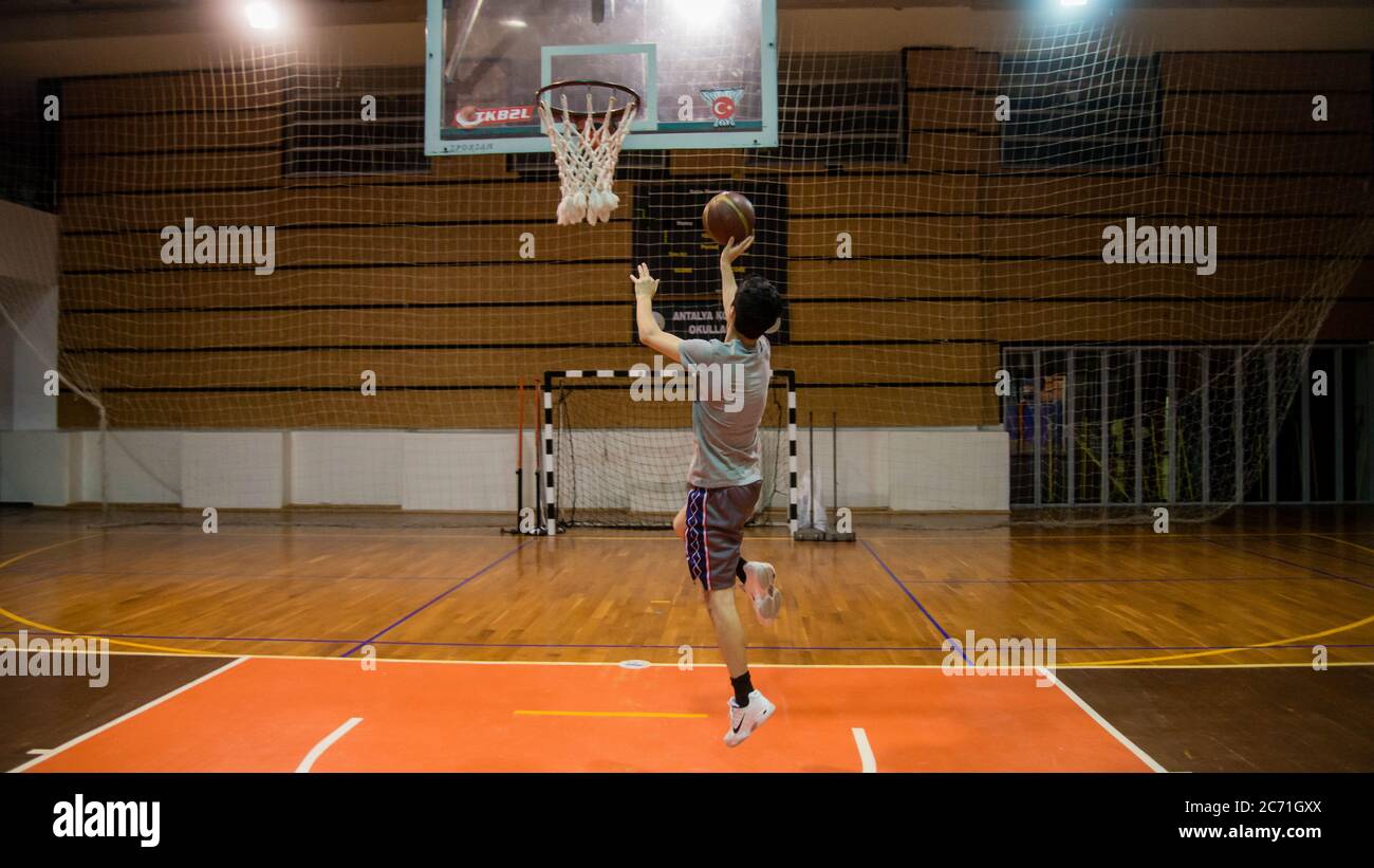 Antalya - Turkey - October 17, 2013: Young man practicing basketball alone in arena Stock Photo
