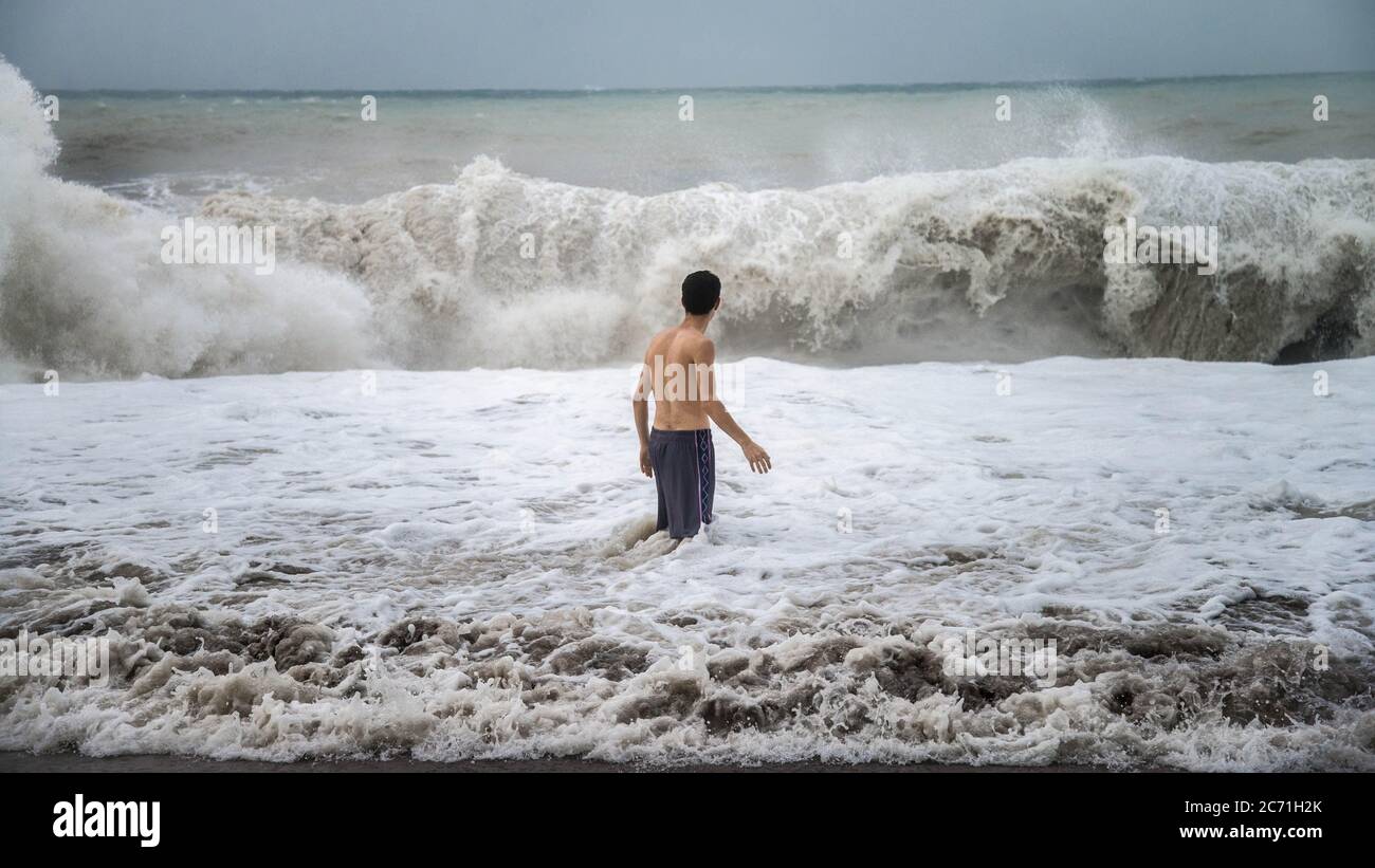Antalya Turkey October 17, 2013 Young man standing against the sea waves with splash in a