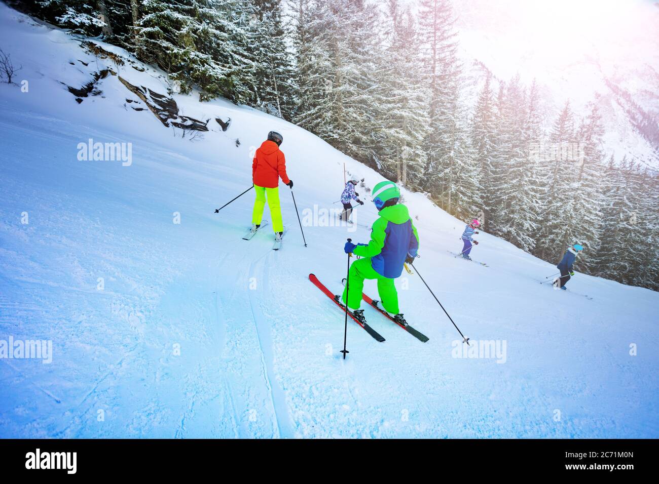 Kids learn skiing down one after another view from behind Stock Photo