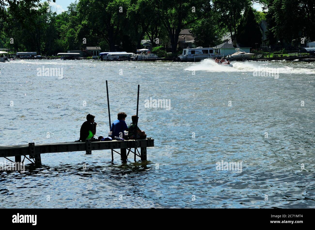 Three young boys having lunch on end of river pier. Stock Photo