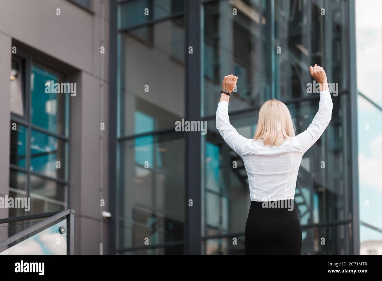 Woman happy about business success. Elegant female office worker celebrates success on the roof of a business center building Stock Photo