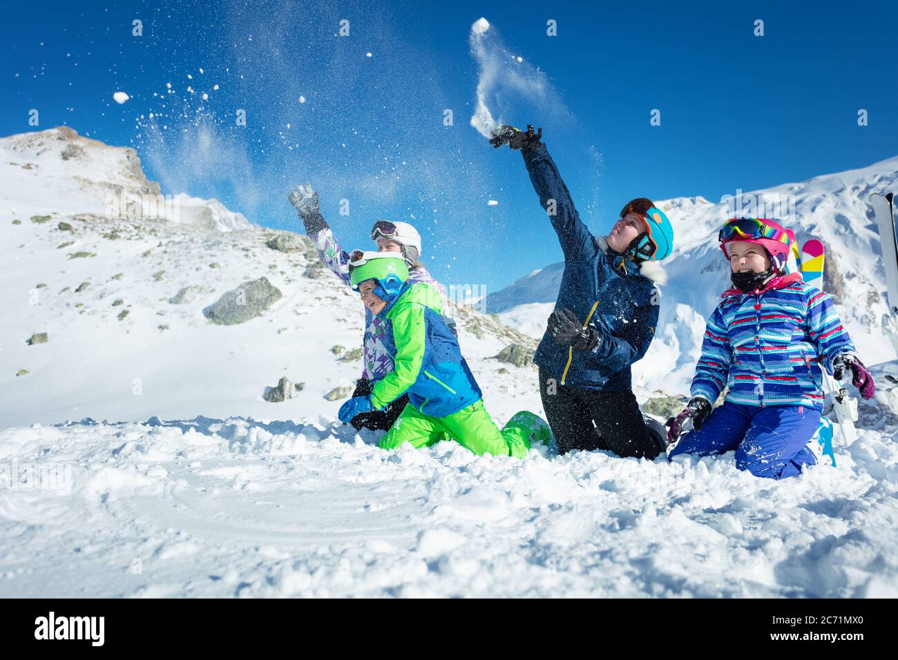 Group of kids play in snow throwing snowballs in ski outfit playing fun