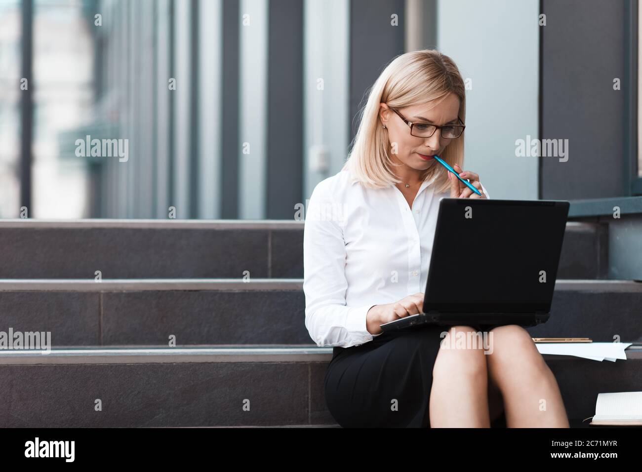 Busy business woman working on laptop outdoors Stock Photo - Alamy