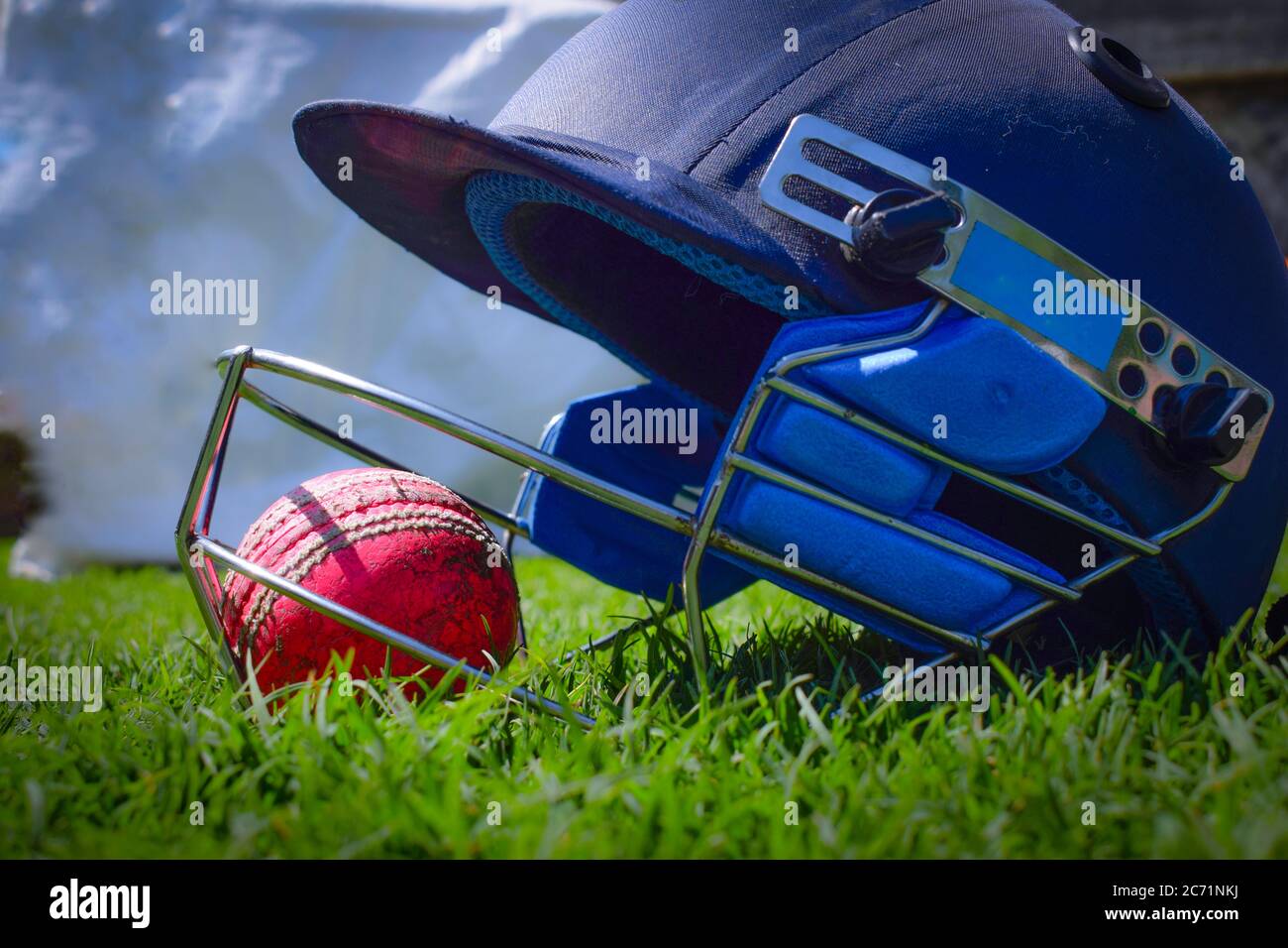 Cricket Halmet And A Ball On A Green Grass Helmet Protects Batsman Cricket Halmet And A Ball On A Green Grass Helmet Protects Batsman