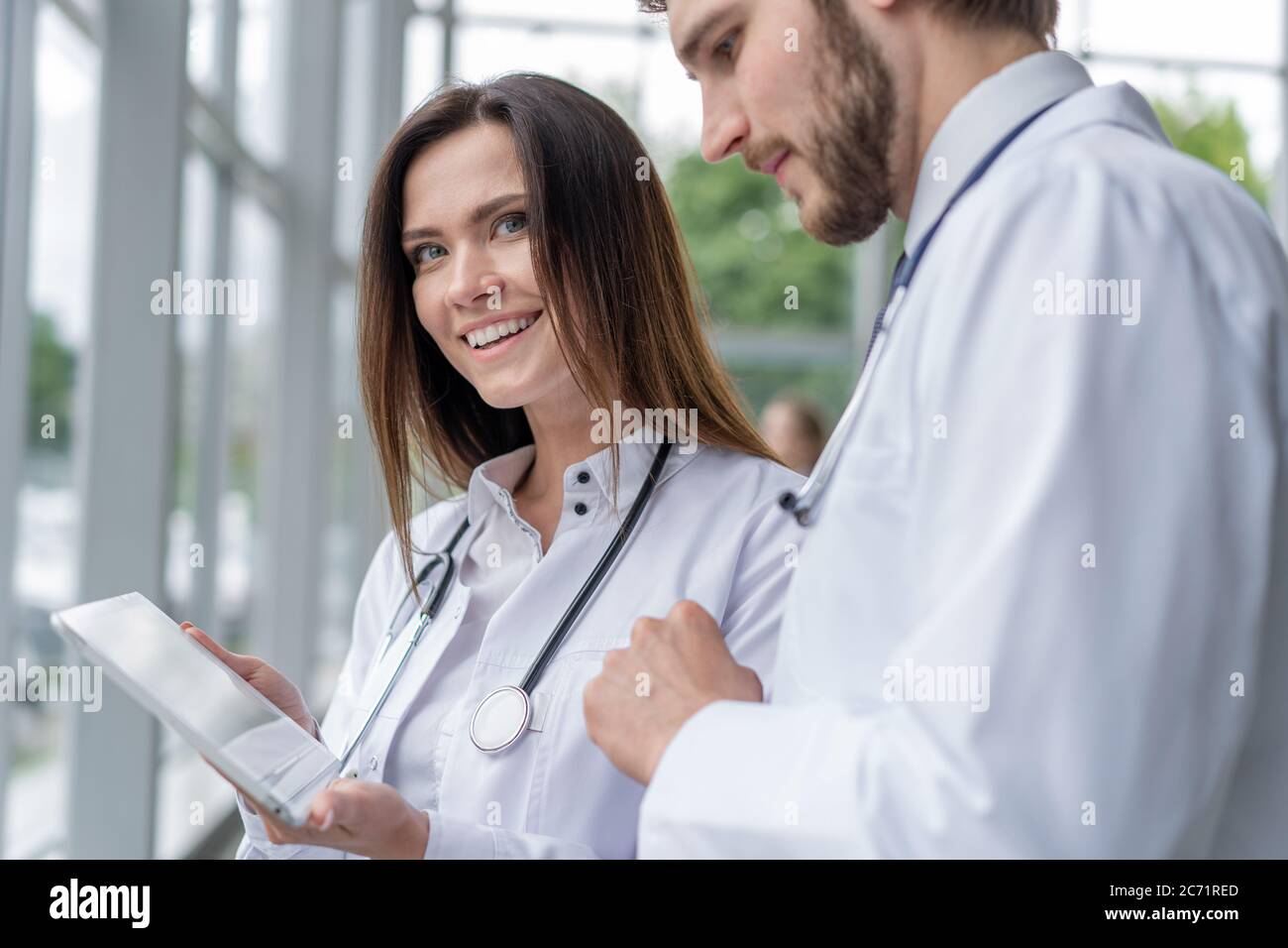 Male doctor using digital tablet with female colleague in hospital, working together. Stock Photo