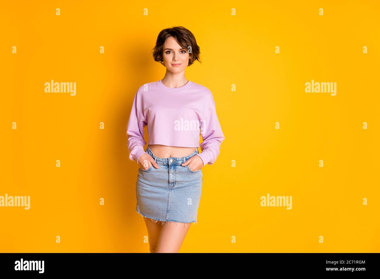 Portrait of her she nice attractive lovely charming content girl holding hands in pockets isolated on bright vivid shine vibrant yellow color Stock Photo