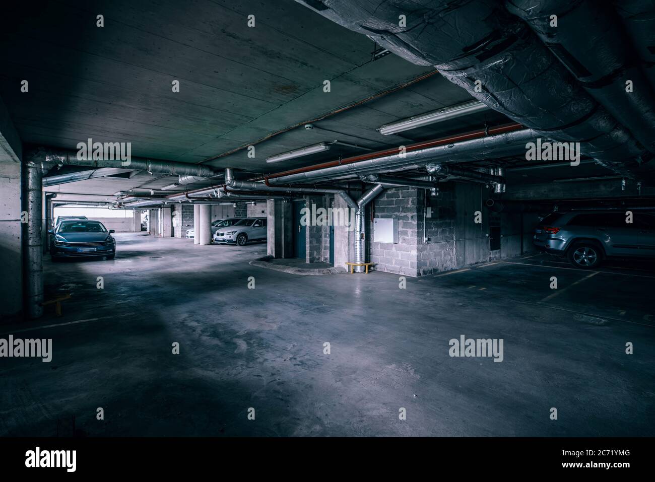 Cars on the underground parking. Interior of garage in industrial building. Concrete floor, brick walls. Stock Photo