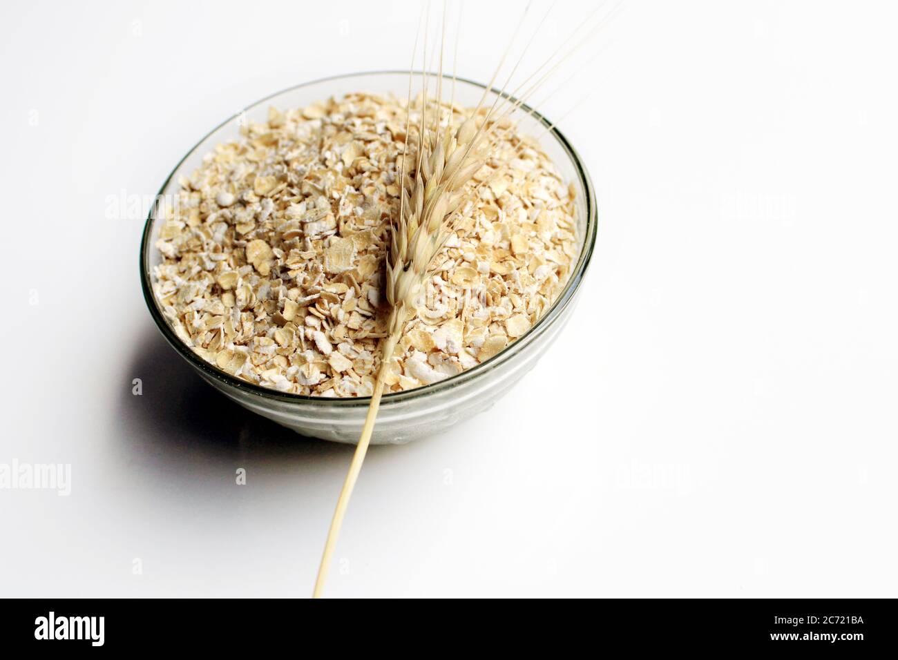 Bowl full of oats. Porridge oats in cereal bowl on white background. A bowl of whole oats isolated on a white. Healthy Eating concept-Oat Flakes. Stock Photo