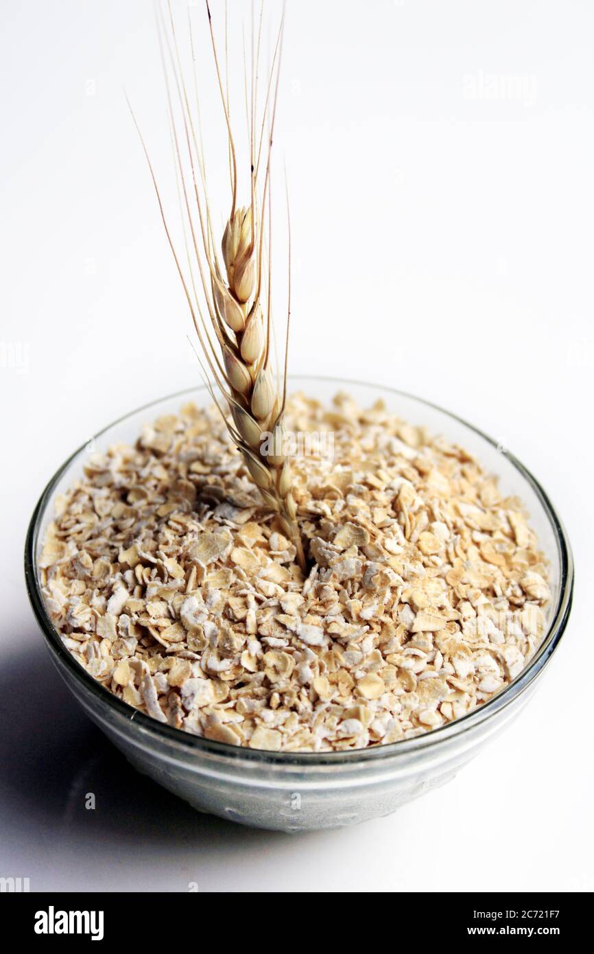 Bowl full of oats. Porridge oats in cereal bowl on white background. A bowl of whole oats isolated on a white. Healthy Eating concept-Oat Flakes. Stock Photo