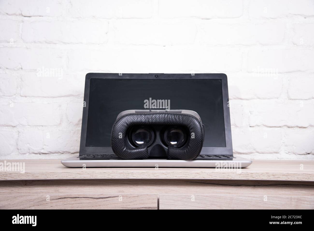 3d glasses and laptop on a wooden table against a brick wall Stock Photo