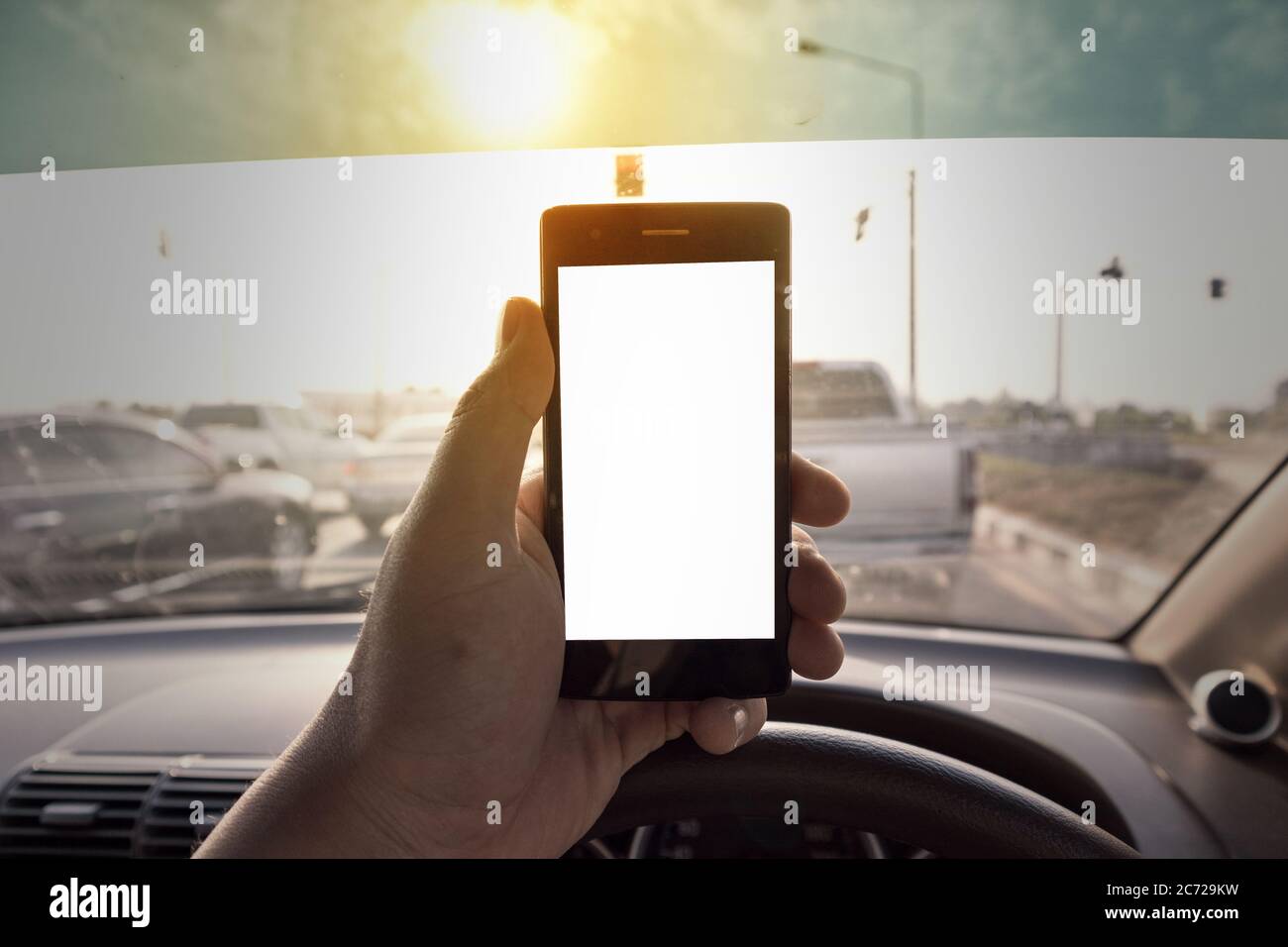 hand holding black smartphone Have space to enter text with white screen at isolated background Use your mobile phone while driving Stock Photo
