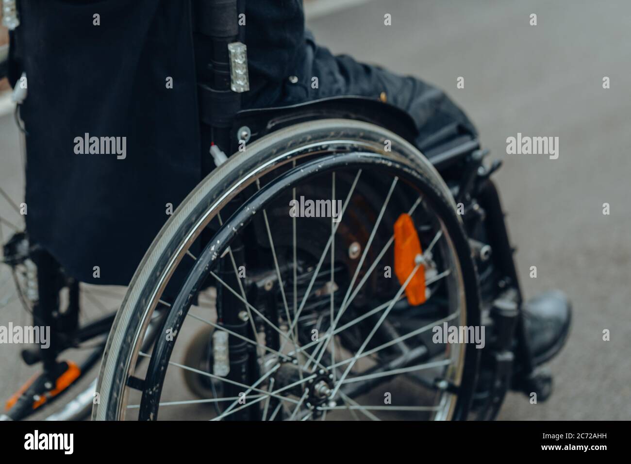 Close-up of male hand on wheel of wheelchair during walk in park. He ...