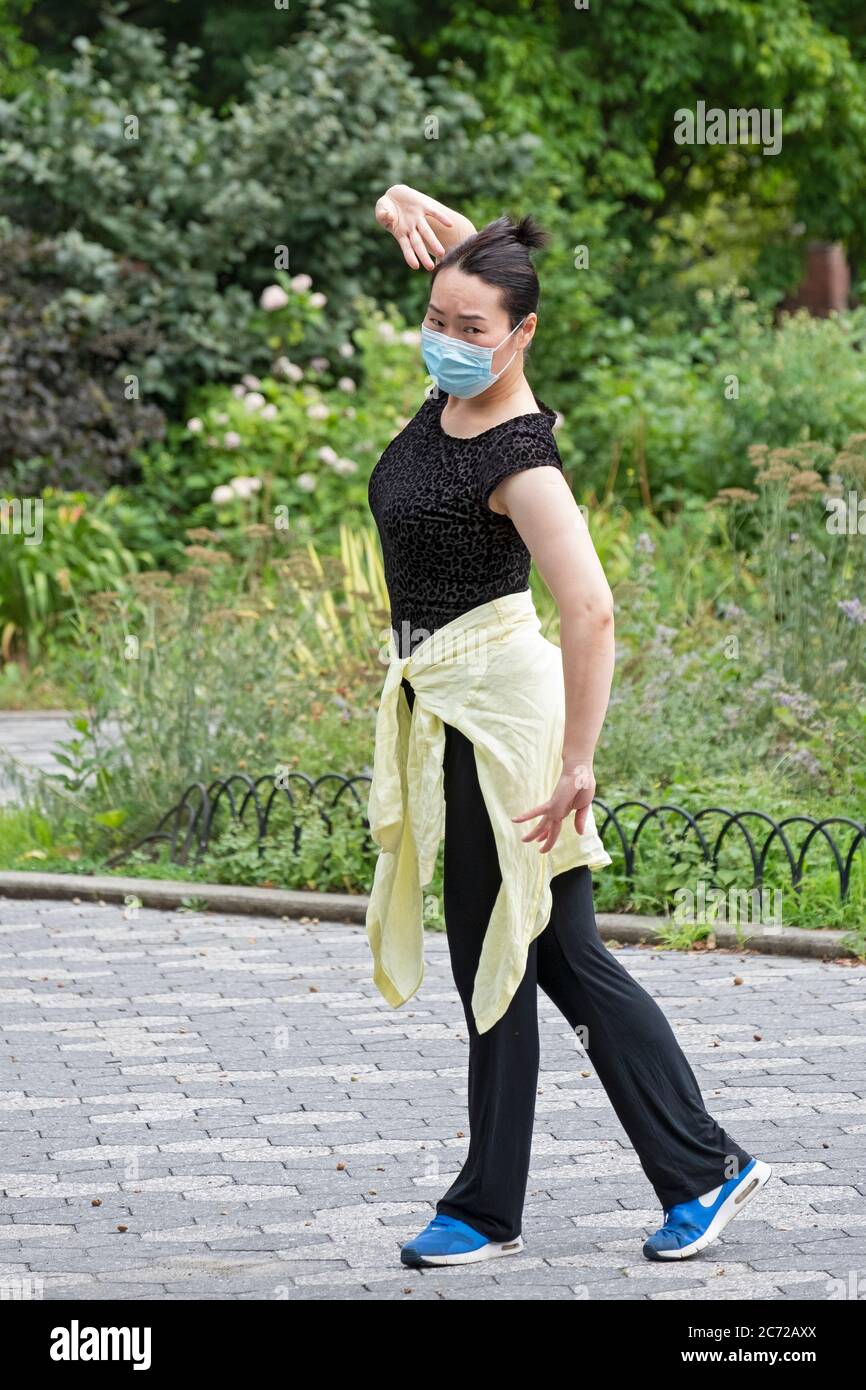 A young attractive Asian American woman  practices modern Chinese dance. In Kissena Park, Flushing, New York City. Stock Photo
