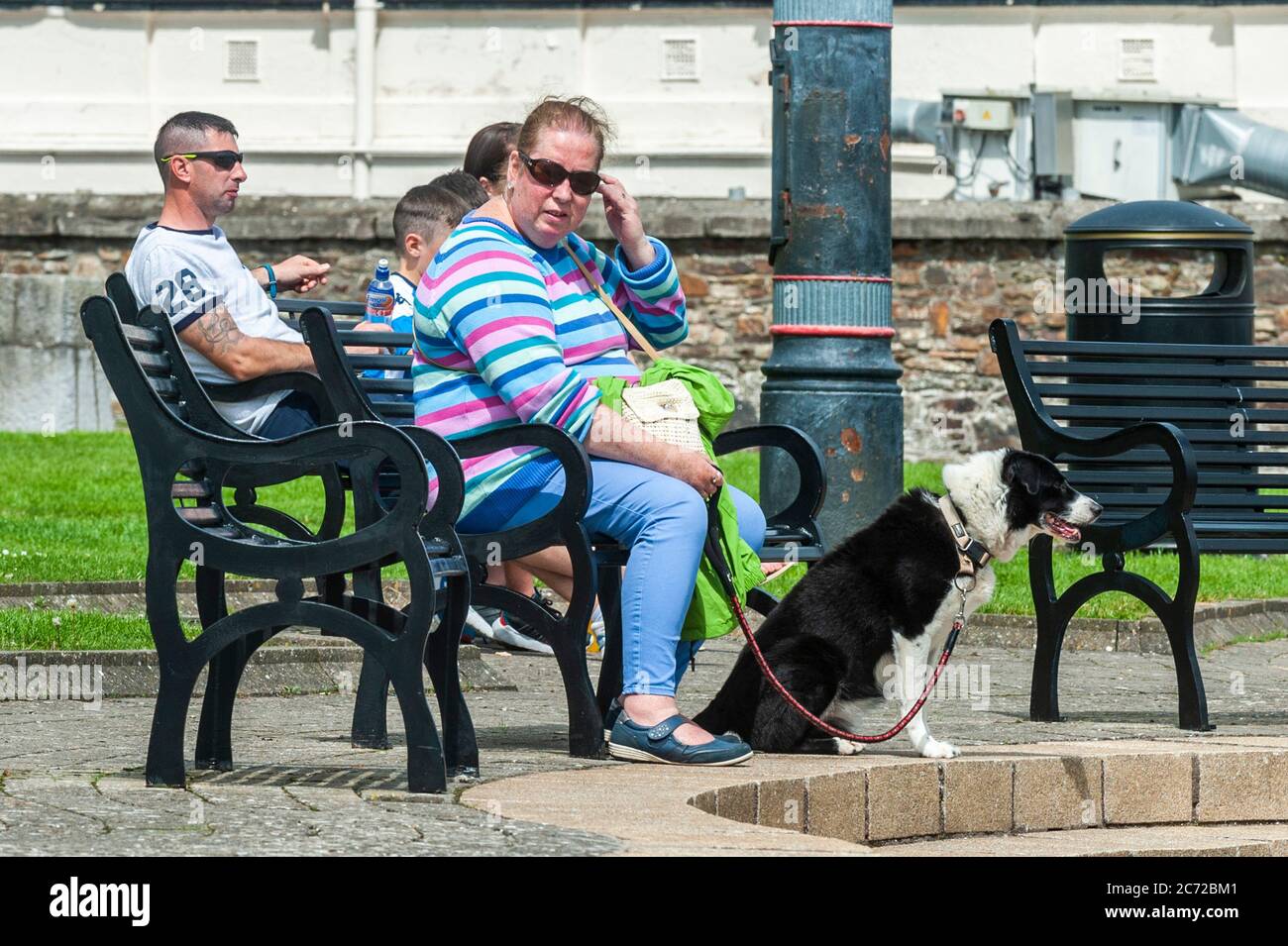 Cobh, County Cork, Ireland. 13th July, 2020. On an overcast but humid day, people enjoy the President John F. Kennedy Memorial Park on the sea front in Cobh. Credit: AG News/Alamy Live News Stock Photo