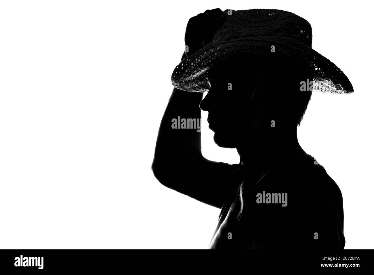 Young man holds the hand hat silhouette - side view Stock Photo