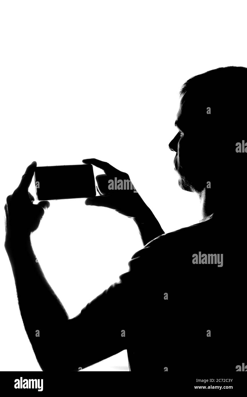 Young man with the phone in his hands - silhouette Stock Photo
