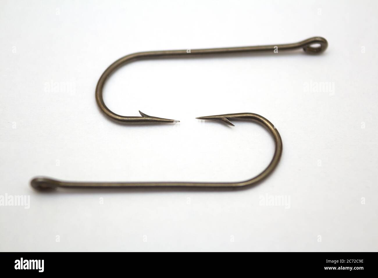 Two fishing hooks on a white paper background - closeup Stock Photo