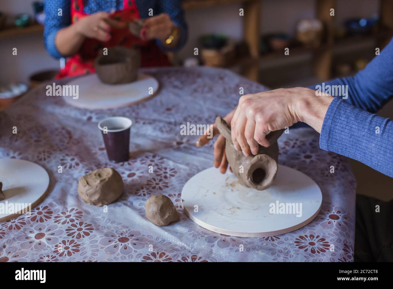 Pottery class and people making clay mugs in pottery studio