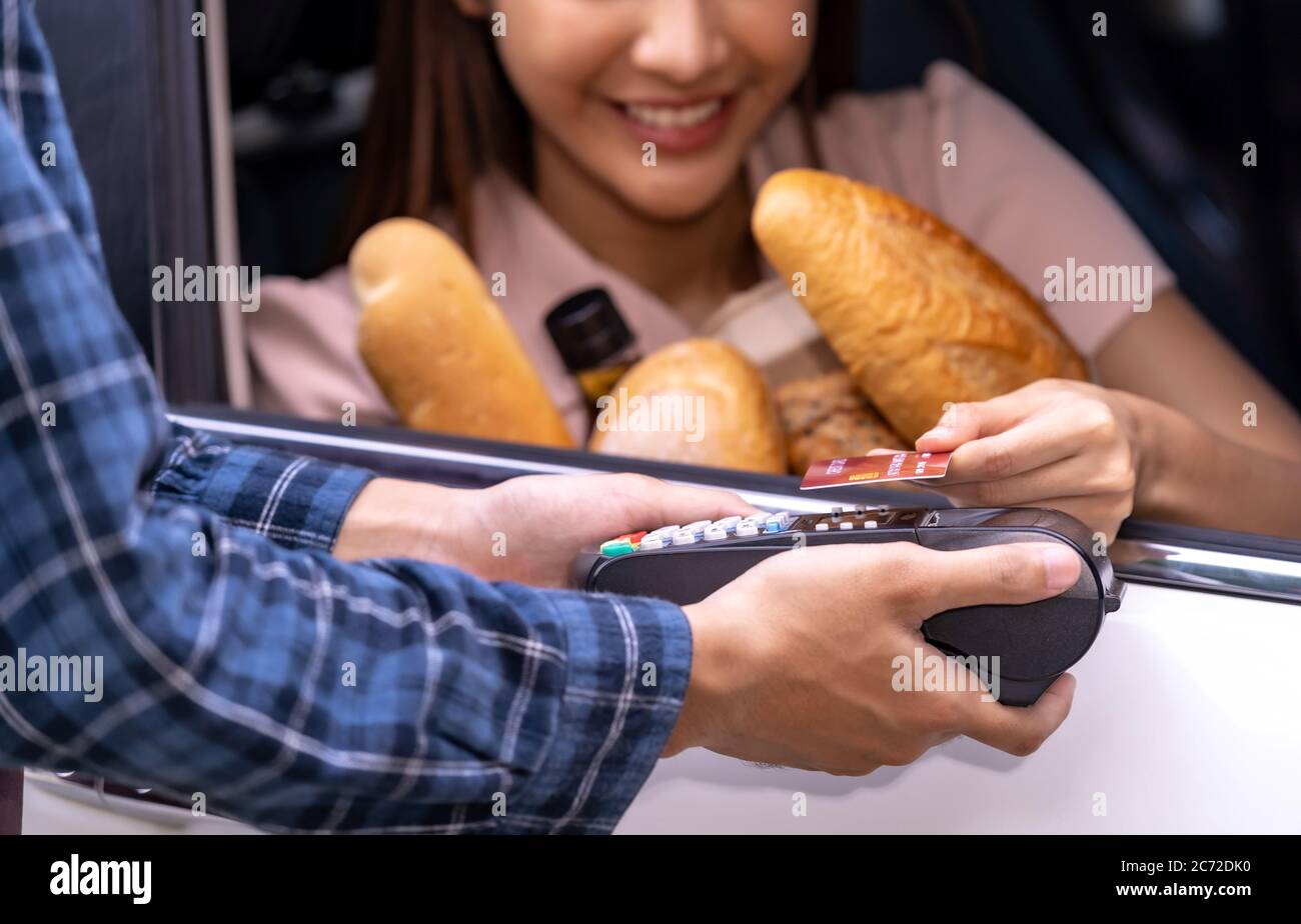 Close up of asian woman make mobile payment contactless technology for online grocery ordering and drive thru service. Drive through and food online i Stock Photo