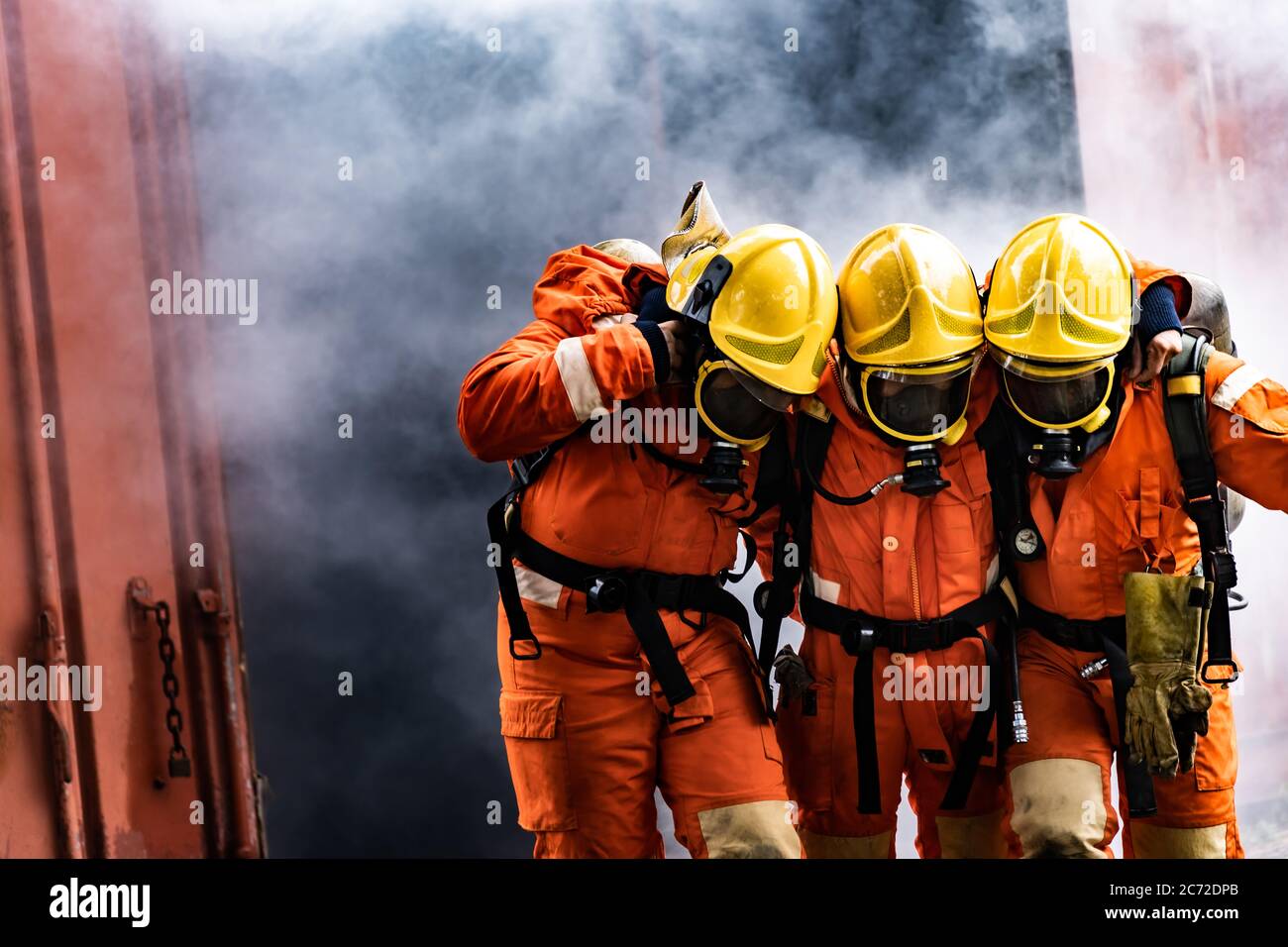 Asian firefighters rescue their team colleague from from burning building. Firefighter safety rescue from accident and public service concept. Stock Photo