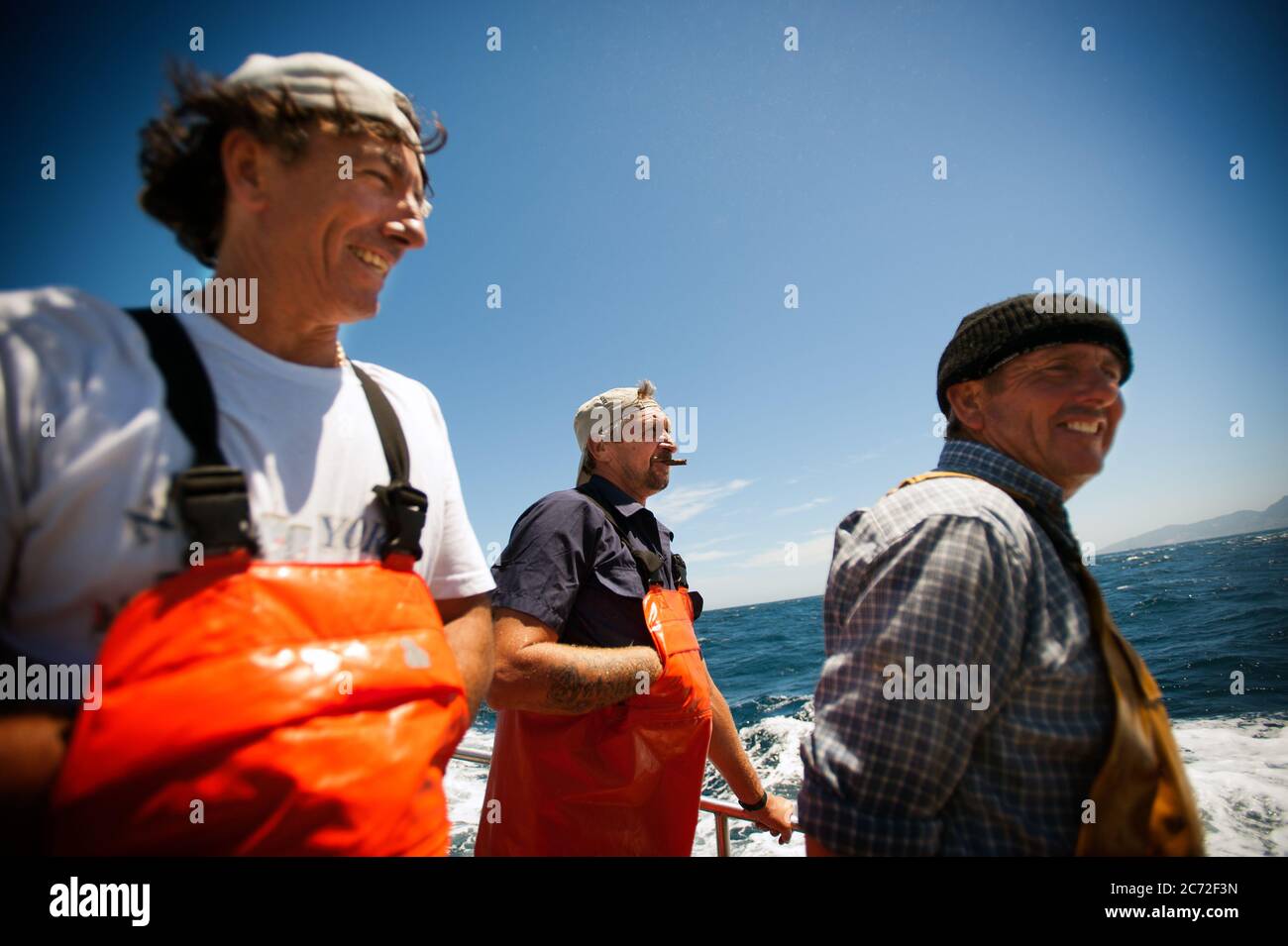 From left to right: Antonio Gomez (a.k.a El Capi), Antonio Dominguez (a.k.a Nono) and Jose Luis Ribella (a.k.a Cosco) talk on the deck of the Fernandez y Moreno fishing boat. Stock Photo