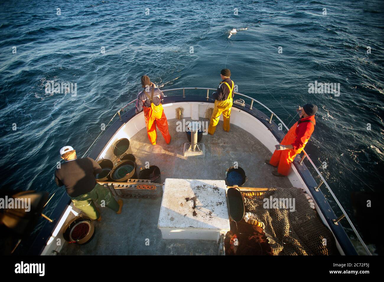 The fishermen crew of the Fernandez y Moreno stand at the stern part of the boat holding fishing lines in their hand. Stock Photo