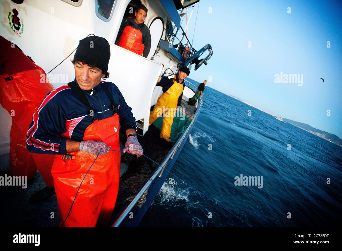 Antonio Gomez (a.k.a El Capi) fisherman of the Fernandez y Moreno fishing boat, holds steady of the fishing line after a  bluefin tuna (Thunnus thynnus) got stuck to it. Stock Photo