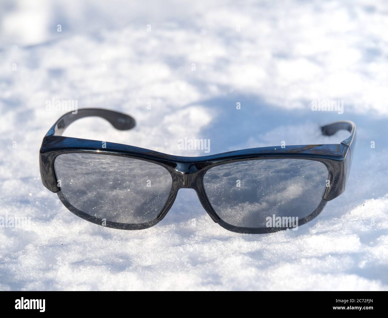 sunglasses on a snow bank at winter resort with reflection of the sun