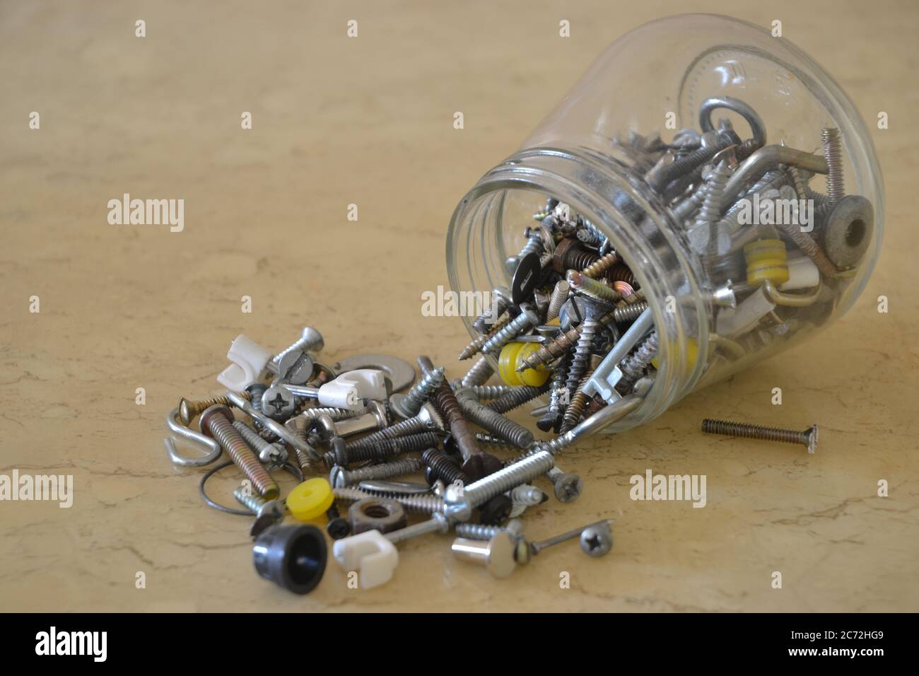 Glass pot with screws, nuts, plastic and washers on marble table, home workshop, photo in zoom, Brazil, South America Stock Photo