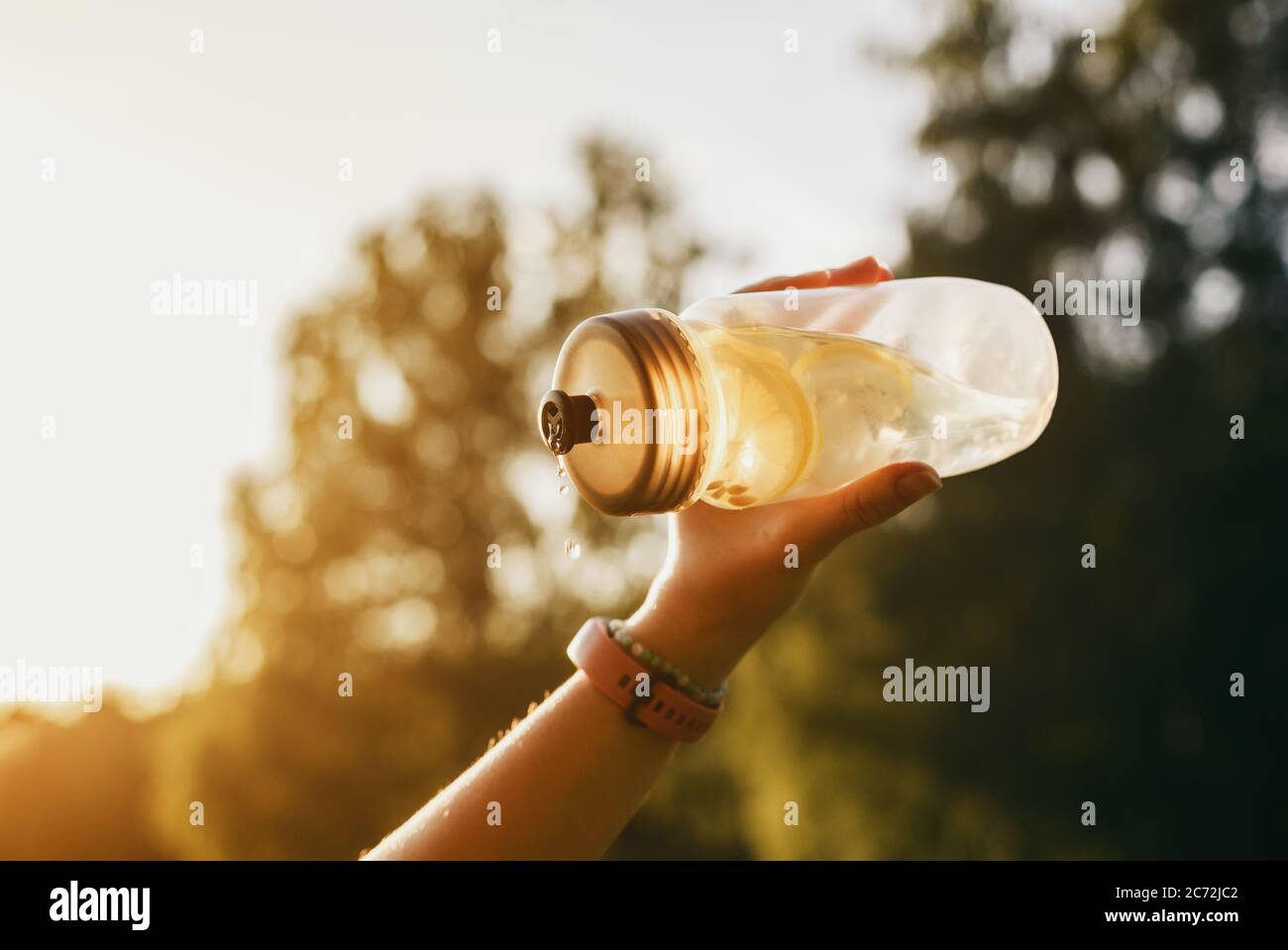 https://c8.alamy.com/comp/2C72JC2/hand-holds-cold-lemonade-in-plastic-bottle-in-contrast-light-2C72JC2.jpg