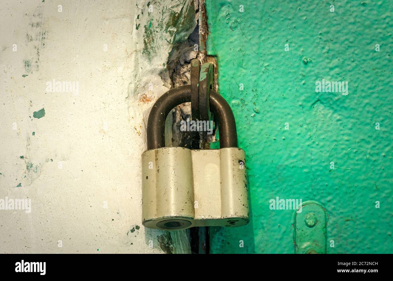 Locked old iron padlock on a green door. Close-up Stock Photo