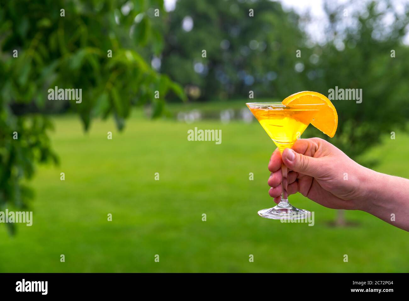 hand with a glass of aperetive at a garden party Stock Photo