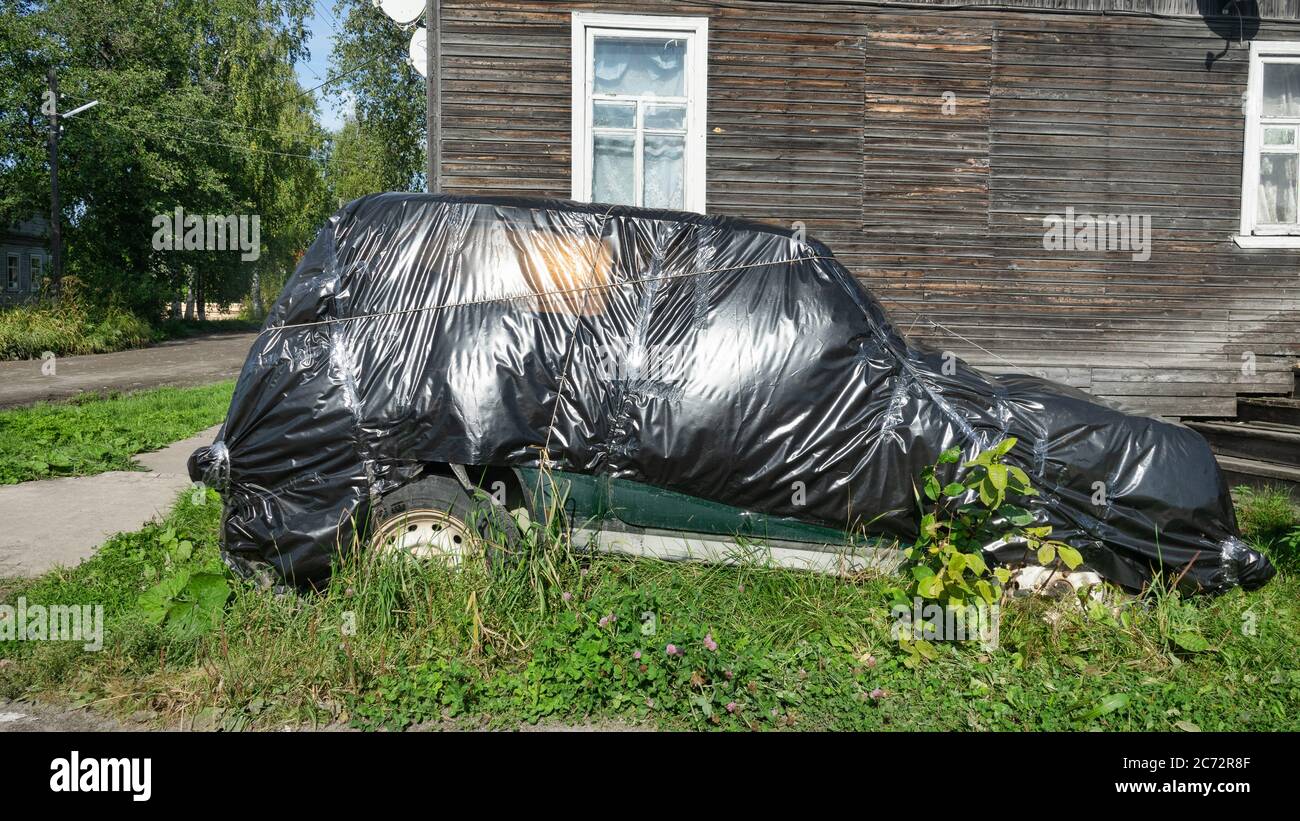 Car in front of house in storage. Auto wrapped in polythene case for long-term storage. Stock Photo