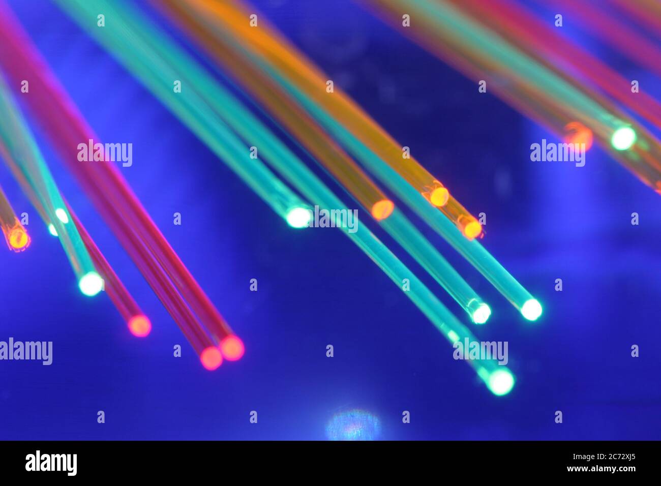 Colorful light emitting fiber optic fiber strains on a blue background. Stock Photo