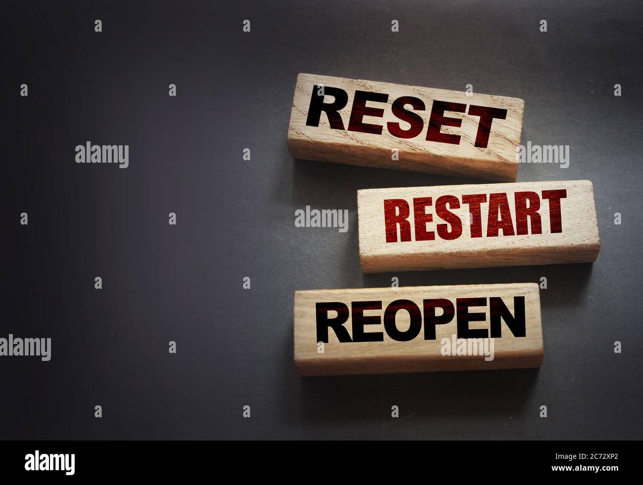 Reset, restart, reopen on wooden blocks on black . Post pandemic world concept Stock Photo