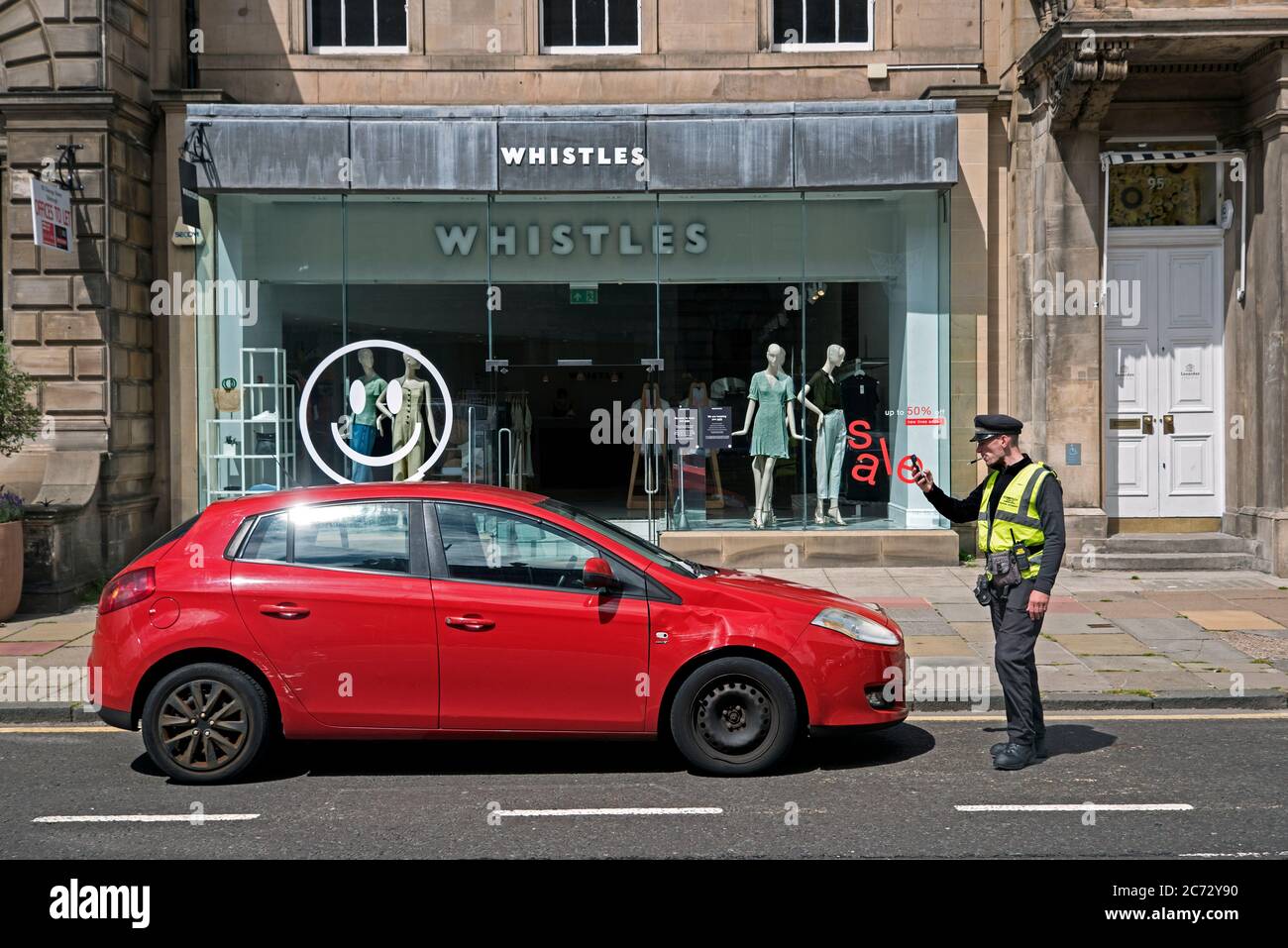 Car being photographed by a traffic warden after being booked outside the Whistles store on George Street, Edinburgh, Scotland, UK. Stock Photo