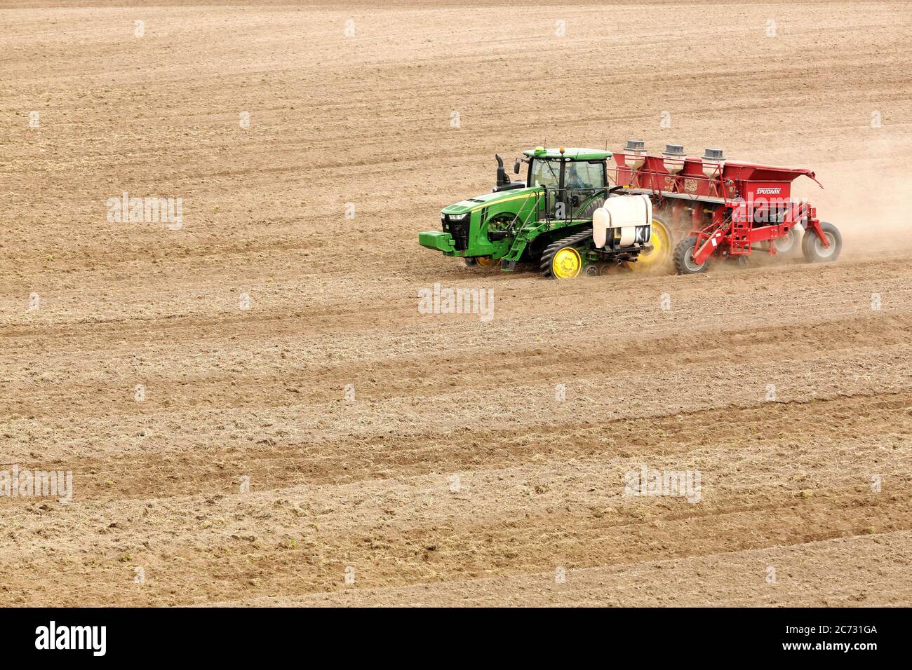 A farmer and tractor in the field planting potatoes in the fertile farm fields of Idaho. Stock Photo