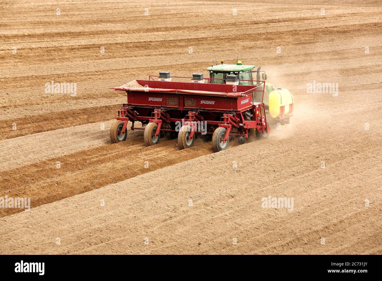 A farmer and tractor in the field planting potatoes in the fertile farm fields of Idaho. Stock Photo