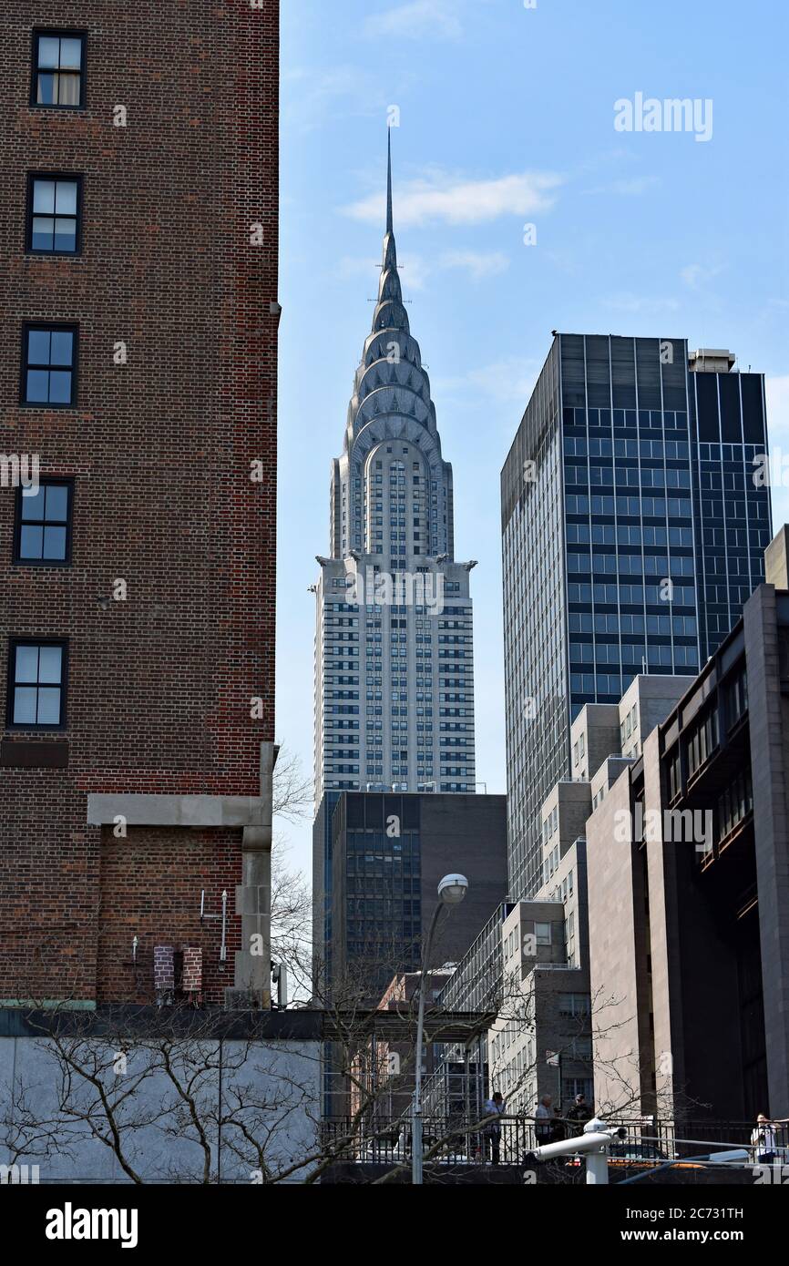 The art deco Chrysler Building seen looking down a street in New York City.  Other buildings are on either side of the street leading the way. Stock Photo