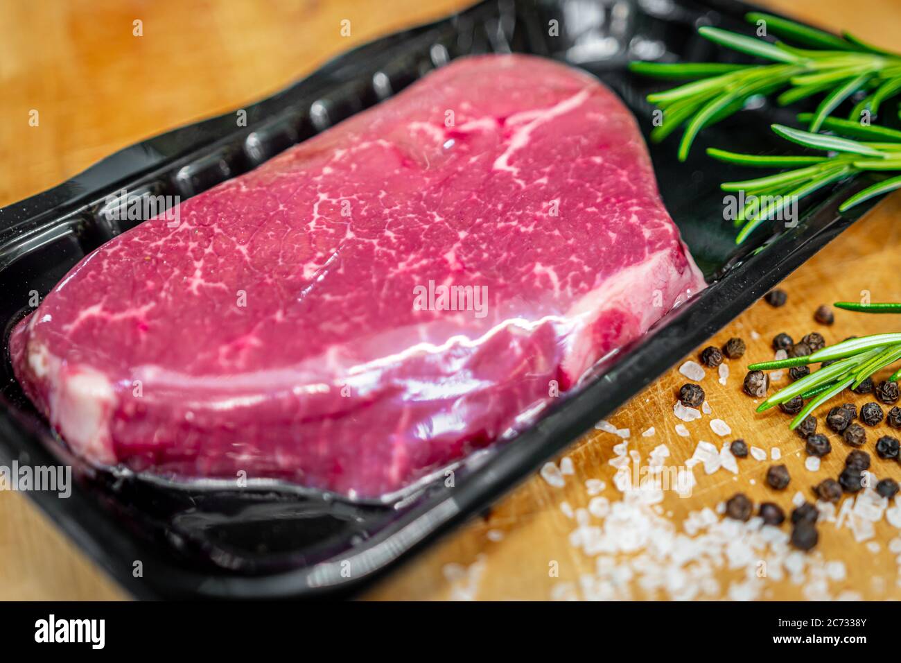 Beef steak in vacuum skin packaging and spices on wooden chopping board Stock Photo