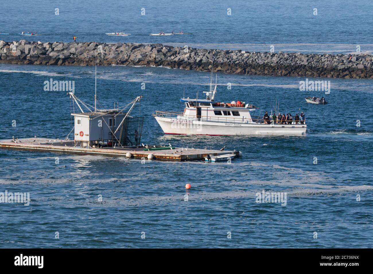 Fishing boat inside Newport Beach harbor jetty visiting a bait barge