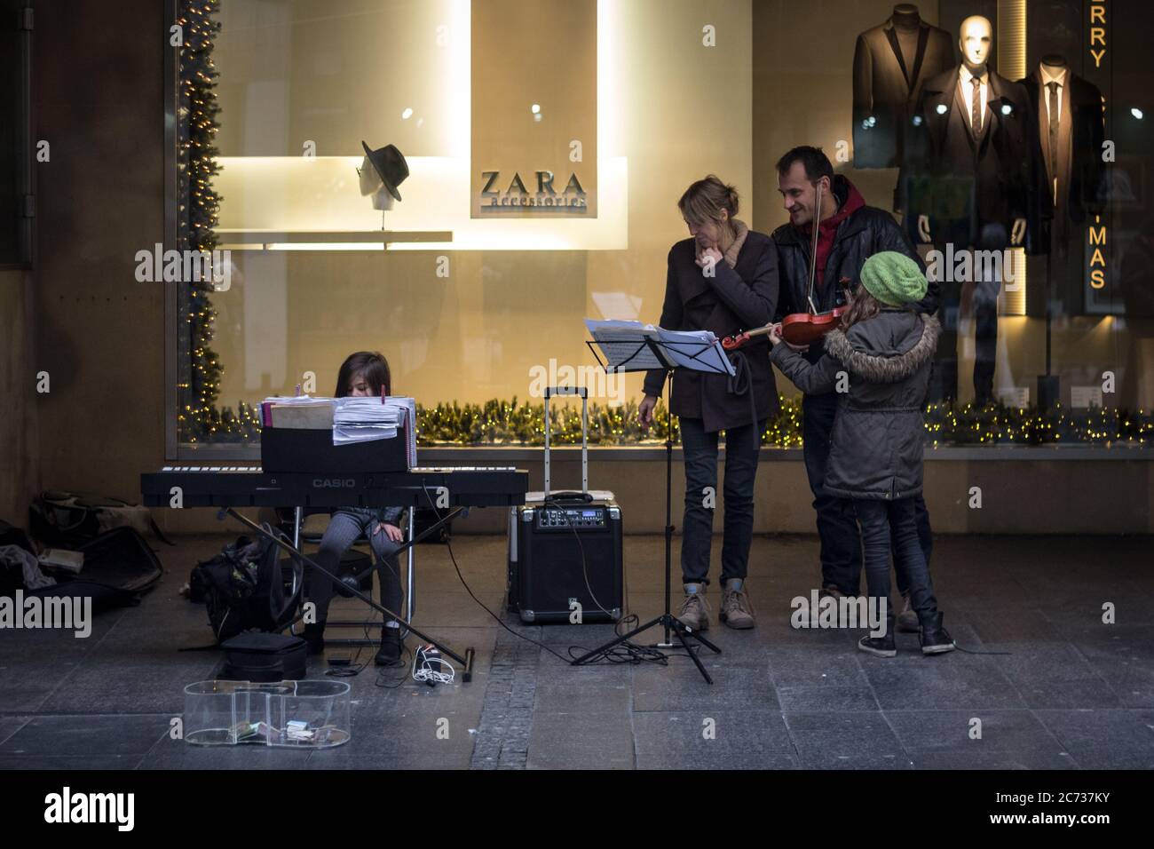 BELGRADE, SERBIA - DECEMBER 6, 2015: Family of musicians, pianists and violonists, performing in a street of Belgrade, observing and admiring the kid Stock Photo