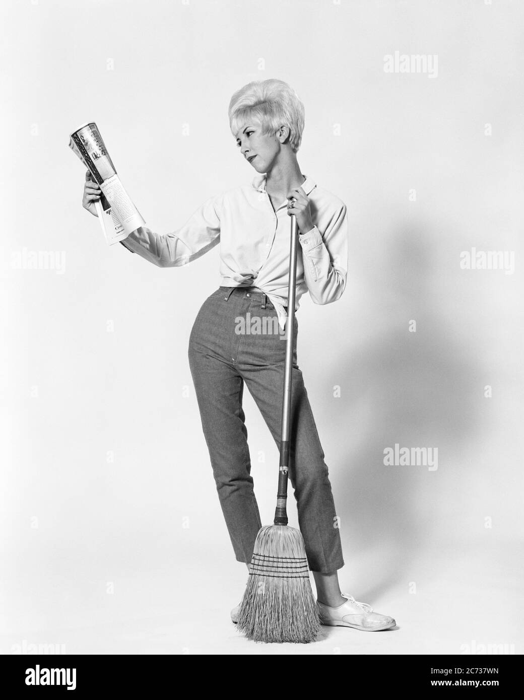 1960s BLONDE WOMAN BOUFFANT HAIRDO HOLDING BROOM READING MAGAZINE DOING HOUSEWORK CLEANING WEARING JEANS BLOUSE TIED MIDRIFF - asp jo7393 ASP001 HARS LIFESTYLE FEMALES STUDIO SHOT HEALTHINESS HOME LIFE COPY SPACE FULL-LENGTH LADIES PERSONS DOING BROOM DENIM B&W BEEHIVE GOALS HOMEMAKER HUMOROUS LAZY HOMEMAKERS STYLES SWEEPING COMICAL OPPORTUNITY BLOUSE HOUSEWIVES CONNECTION COMEDY ESCAPE STYLISH SUPPORT BLUE JEANS DISTRACTED FASHIONS HAIRDO INFORMAL MID-ADULT MID-ADULT WOMAN MIDRIFF SWEEP TEASED TWILL YOUNG ADULT WOMAN BLACK AND WHITE BOUFFANT CASUAL CAUCASIAN ETHNICITY DIVERSION OLD FASHIONED Stock Photo