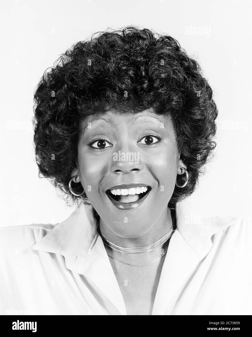 1970s WIDE-EYED LAUGHING ENTHUSIASTIC AFRICAN-AMERICAN WOMAN NATURAL HAIRSTYLE LOOKING AT CAMERA - g8617 HAR001 HARS EYE CONTACT BUG-EYED HAPPINESS HEAD AND SHOULDERS CHEERFUL AFRICAN-AMERICANS AFRICAN-AMERICAN EXCITEMENT HAIRSTYLE BLACK ETHNICITY ENTHUSIASTIC NATURAL SMILES CONCEPTUAL CHEERY JOYFUL LAUGHTER WIDE-EYED YOUNG ADULT WOMAN BLACK AND WHITE EXUBERANT HAR001 MOUTH OPEN OLD FASHIONED AFRICAN AMERICANS Stock Photo