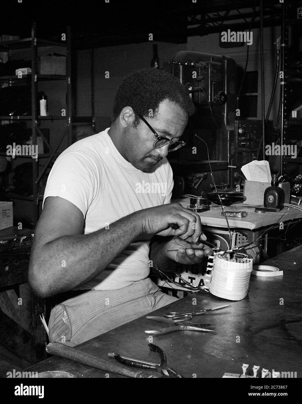 1960s 1970s SKILLED MAN AFRICAN-AMERICAN ELECTRICAL TECHNICIAN REBUILDING REPAIRING AN INDUSTRIAL MACHINE COMPONENT IN SHOP - i5239 HAR001 HARS B&W SUCCESS SKILL OCCUPATION SKILLS STRENGTH CUSTOMER SERVICE AFRICAN-AMERICANS AFRICAN-AMERICAN CAREERS KNOWLEDGE POWERFUL PROGRESS BLACK ETHNICITY INNOVATION PRIDE AN IN OPPORTUNITY MANUFACTURING OCCUPATIONS REPAIRING COMPONENT CONCEPTUAL IMAGINATION STYLISH SKILLED CREATIVITY MID-ADULT MID-ADULT MAN PRECISION BLACK AND WHITE CONCENTRATION HAR001 OLD FASHIONED AFRICAN AMERICANS Stock Photo